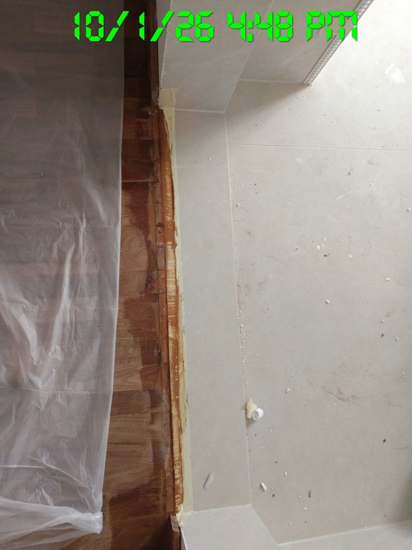 Plastic sheet taped along a tiled area next to parquet