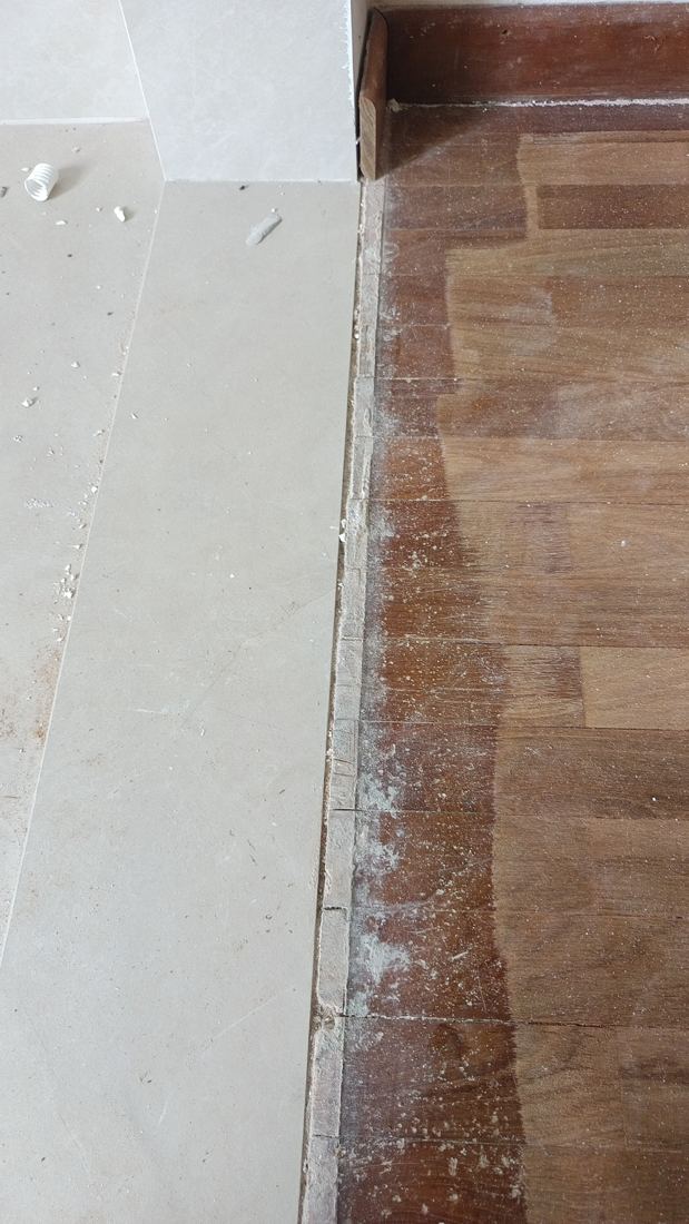 Clean edge where sanded parquet meets floor tiles