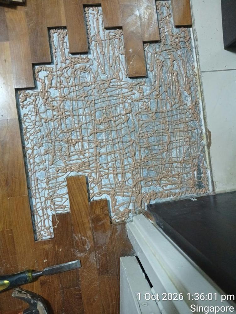 Loose parquet lifted in a Toa Payoh flat, showing old adhesive on the screed