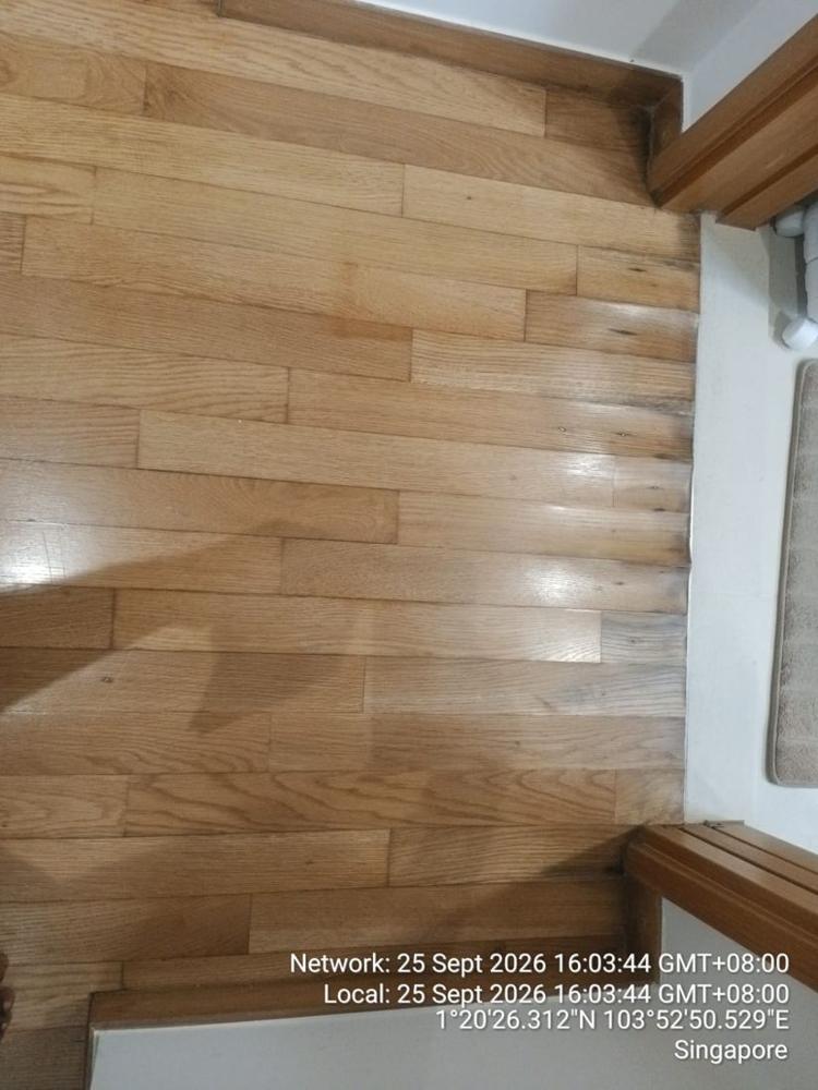 Worn oak strip floor with grey patches at a doorway
